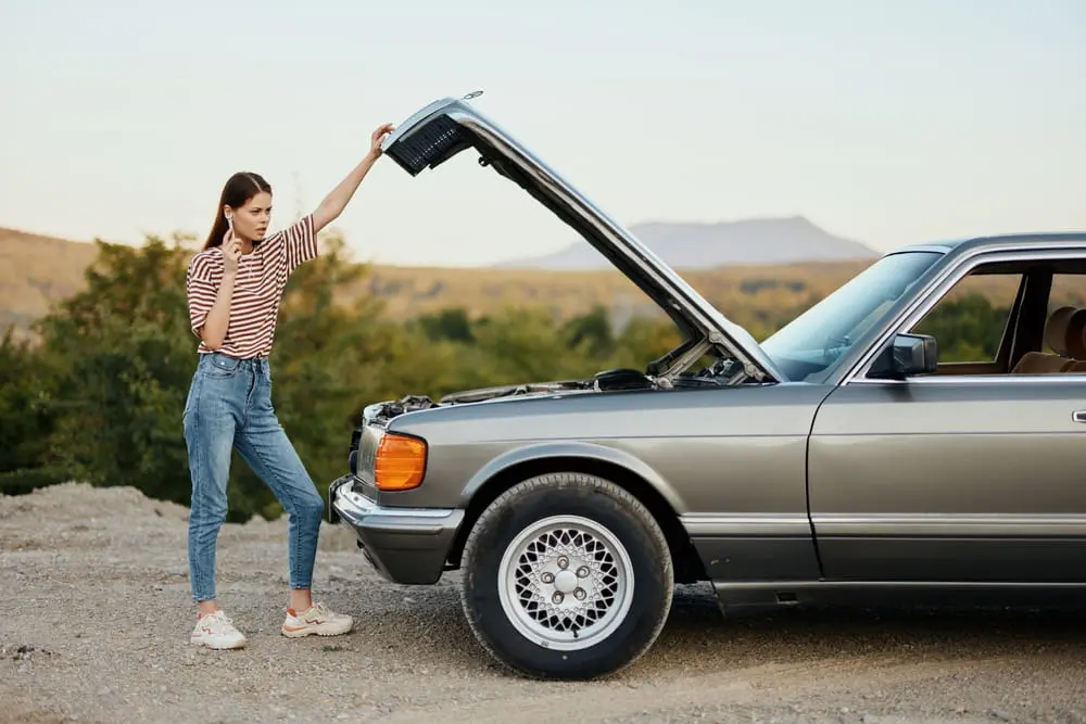 Woman Looking At The Motor Of Her Car While Talking On The Phone