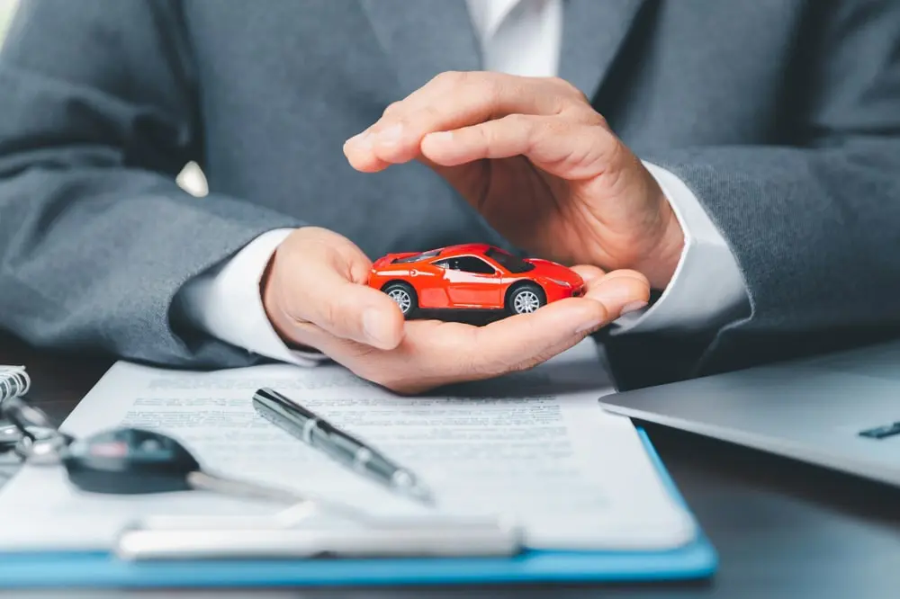 Man In A Suit Holding A Red Toy Car